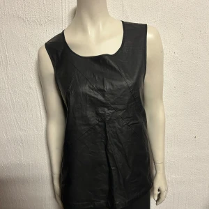 Topp från Desires. Stl S. Konstskinn fram - Tuff topp med konstskinn fram och lite tunnare polyester bak. Storlek S. Från Desires.