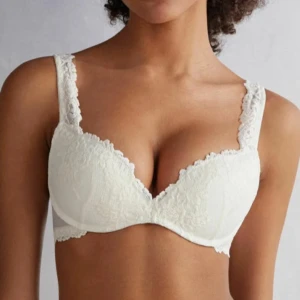 Vit spets-bh med vadderade kupor - Säljer en vit bh med spetsdetaljer och vadderade kupor. Bh:n har breda axelband med spets och ger ett lyxigt intryck. Perfekt för dig som vill ha något både bekvämt och snyggt under kläderna. Den är inköpt för nån månad sen men har inga skador har bara en lite annan färgnyans på baksidan under kupporna men inget som är märkbart och kan skicka bild vid intresse💕slutsåld och nypris runt 590kr