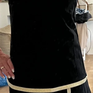 Tenniskjol med matchande topp, stl S - Snyggt set med tenniskjol och topp från Atelier Capri. Svart med guldkanter, storlek S. Aldrig använt. Nypris ca 1800kr