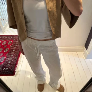 Vita Lågmidjade linnebyxor (ej strykta) - Vita Lågmidjade kostymbyxor från A-Design. Har inte strykt dem. Onesize men skulle säga passar 34-40 beroende på hur man vill att de ska sitta. Spårbar frakt PostNord tillkommer på 67kr