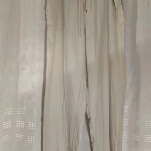 Beige linnebyxor från MNG stl s - Säljer ett par beige linnebyxor från MNG med avslappnad passform och resår i midjan. Byxorna har dragsko och två bakfickor. Perfekta för en stilren och bekväm look.