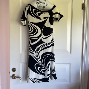 Svartvit mönstrad klänning från OCCO - Säljer en svartvit klänning från OCCO med grafiskt, abstrakt mönster. Klänningen har korta ärmar och en smickrande, något figurnära passform. Perfekt för dig som gillar unika och iögonfallande plagg.