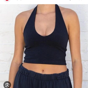 Svart halterneck croppad topp - Säljer en svart croppad halterneck topp med djup urringning. Perfekt för varma dagar eller som ett statement-plagg. Toppens material är mjukt och stretchigt för en bekväm passform.