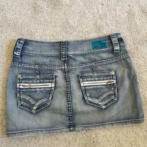 Mini Jeanskjol från Reserved Jeans - Säljer en ljusblå jeanskjol från Reserved Jeans med två bakfickor med dragkedjor och dekorativa sömmar. Kjolen har bälteshällor och klassisk jeansknapp framtill. Perfekt för dig som behöver en snygg miniskirt till sommaren. Midjemått 40cm och längd 30cm💕☀️skriv om du har någon fråga 
