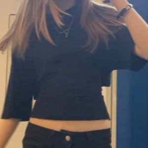 Knyt topp från Nelly - Säljer en svart croppad topp med vida ärmar och snygg knytning i ryggen. Toppen har en enkel design framtill men cool detalj baktill som gör den unik. Perfekt att styla med både jeans och kjol.
