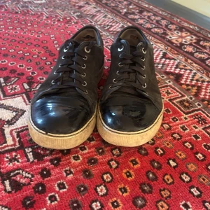 Svarta sneakers från Lanvin Toe cap - Säljer ett par svarta sneakers från Lanvin med snygg kombination av mocka och lackad tå. .Perfekta för dig som vill ha något stilrent men ändå unikt. Obs! Kan gå ner i pris vid snabb affär