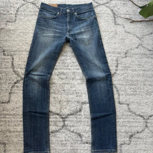 Blå jeans från dondup - Snygga blå skinny jeans från Dondup med slitningar framtill och coola dragkedjor på bakfickorna. Jeansen har klassisk femficksdesign, låg midja och smal passform. Perfekta för dig som gillar en modern och edgy stil. Priset är ej hugget i sten!