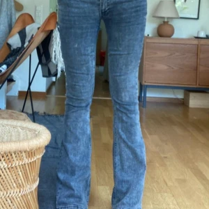 Svarta bootcut jeans - Säljer ett par svarta bootcut jeans med klassisk femficksdesign och knappgylf. Jeansen har en väldigt låg mudja och är i ett stretchigt denimtyg som sitter snyggt över höfterna och låren innan de släpper ut vid bensluten. Omsydda själv till low waist, kan skicka bild på det ifall önskat❤️
