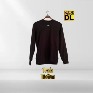 Svart sweatshirt från Prada - Svart sweatshirt från Prada med klassisk rund halsringning och diskret logga i metall på bröstet. Tröjan har lång ärm, ribbade muddar och är gjord i mjuk bomull. Perfekt för dig som gillar stilren och lyxig streetwear.