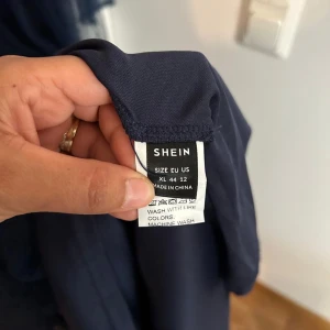 Marinblå spetsklänning från SHEIN XL - Marinblå långklänning från SHEIN med transparenta långärmar i mesh och prickigt mönster. Livet har vacker blommig spets och kjolen är i flera lager tunn polyester. Dragkedja bak för enkel påklädning. Perfekt för dig som vill sticka ut med en elegant look.