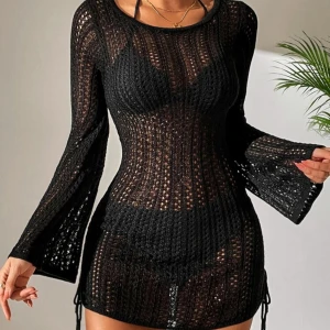 Svart stickad kortklänning - Snygg svart stickad kortklänning med långärmade utsvängda ärmar och transparent virkad look. Perfekt att dra över bikinin på stranden eller till sommarens häng. Figurnära passform och rund halsringning.