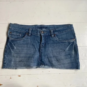 Jeanskjol med broderade fickor  - Snygg blå jeanskjol med rå kant nertill och broderade bakfickor med pärldetaljer. Klassisk femficksmodell med bälteshällor och knappstängning framtill. Perfekt för dig som gillar en chill och trendig stil. Pris kan diskuteras! 