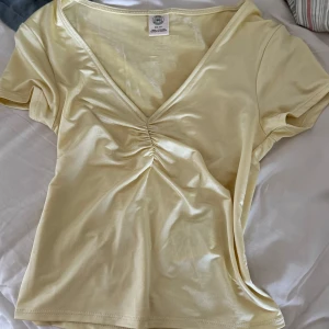 Ljusgul topp Urban Outfitters - Supersöt ljusgul topp från Urban Outfitters med v-ringning och stretchigt, lite glansigt material 💛💛💛