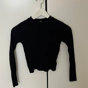 Svart ribbad långärmad tröja XS - Svart ribbad långärmad tröja från H&M i storlek XS. Tröjan har en tight passform och är tillverkad i mjukt, stretchigt material. Perfekt att styla med jeans eller kjol för en clean look.