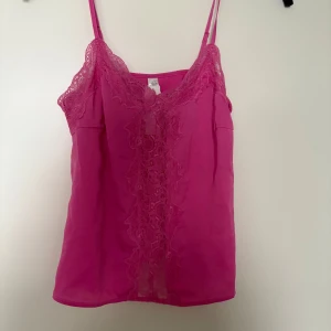 Rosa linnetopp med spetsdetaljer XS - Säljer en snygg rosa linnetopp från Lindex i storlek XS. Toppen har tunna axelband och v-ringning med dekorativa spetsdetaljer framtill. Tillverkad i återvunnen polyester för en lätt och luftig känsla. Perfekt för att lyfta vilken outfit som helst.