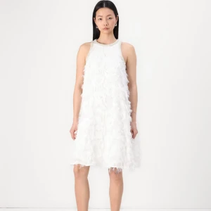 Vit kortklänning med pärldetaljer från YAS - Superfin vit cocktailklänning från YAS med pärldetaljer runt halsringningen samt ett unikt texturerat tyg med fjäderliknande detaljer. Klänningen är helt oanvänd, jag är villig att sänka priset för en snabb affär. 