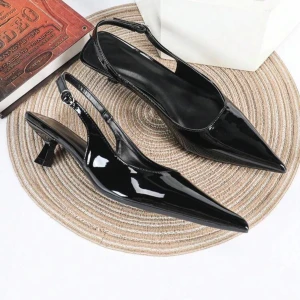 Svarta lackade pumps med spetsig tå - Snygga svarta pumps i lack med spetsig tå och låg klack. Skorna har öppen häl med justerbart spänne och en elegant, glansig finish som ger en riktigt chic vibe. Perfekta för dig som vill sticka ut med stilrena detaljer. Säljer pga för stora aldrig använda 