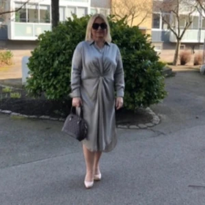 Beige skjortklänning från H&M - Stilren beige skjortklänning, silk från H&M med knappar framtill och snygg twistad detalj i midjan. Långärmad modell i mjukt, glansigt material som ger en lyxig känsla. Perfekt för dig som gillar minimalistisk och clean stil. Hade på mig en gång. Den är stort i storleken.