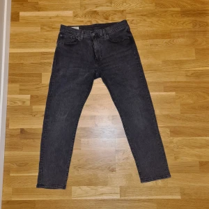 Levi's 502 svarta jeans - Säljer ett par svarta Levi's 502 jeans med klassisk femficksdesign och raka ben. Jeansen har knappgylf och är tillverkade i ett slitstarkt denimtyg. Passar perfekt till dig som gillar en tidlös och enkel stil. W32 L30