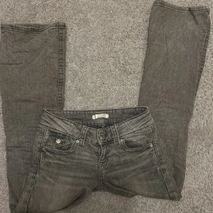 Grå bootcut jeans från Gina Tricot - Snygga grå jeans från Gina Tricot i bootcut-modell. Klassisk femficksdesign med knappar och dragkedja framtill. Jeansen har en lätt tvättad look och passar perfekt till vardagsstilen. Säljer då de är försmå. Skriv gärna innan köp!! Skulle säga att de är en aning ljusare än vad de ser ut på bilden.