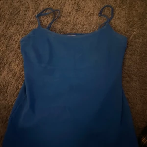 Blå linnetopp från Zara - Säljer en enkel och stilren blå linnetopp från Zara med tunna axelband. Perfekt att matcha med jeans eller kjol för en fräsch look. Toppen är i mjukt material och har en rak passform.