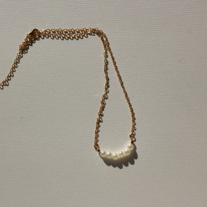 Guldhalsband med pärlor - Snyggt halsband med tunn guldfärgad kedja och små vita pärlor på rad. Perfekt för att ge en elegant touch till din outfit. Passar både till lager-på-lager och som ensam statement. Går och få kedjan i silver. Obs bara ett halsband ingår, paketet priset på sista bilden är 180 kr. 