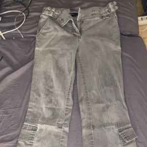 Grå cargopants med detaljer - Säljer ett par grå cargopants från Miss Sixty med lite bootcut, fickor på sidorna och bältesdetaljer i midjan. Stl 36 i dem och perfekt för dig som gillar y2k/grunge/emo/2000s/90s stil. Jag har aldrig använt dessa och har ärvt dem av min mamma som hade dom runt 2000 talet. Pris kan diskuteras❤️