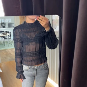 Svart mesh blus  - Säljer denna jätte snygga blusen från Nelly. Det är en mesh blus med paljetter på och jätte fina volang i slutet av ärmarna