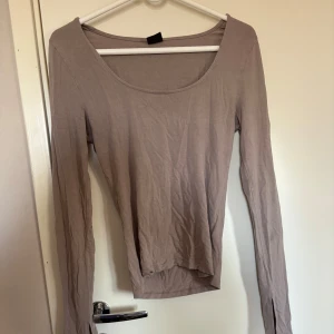 Beige långärmad topp med slits - Säljer en beige långärmad topp från Gina med rund halsringning och slits på armarna