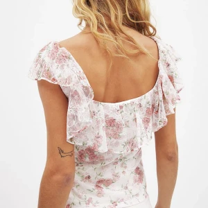 Vit blommig blus med volang - Säljer denna super söta blus från NA-KD💖 helt ny och oanvänd då jag inte hann skicka tillbaka den! Storlek: XS (32)💛