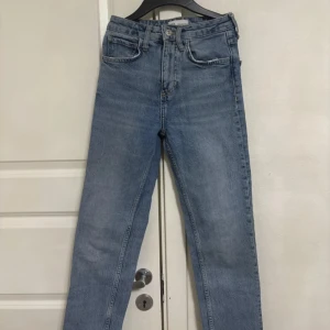 Blå jeans från Zara - Snygga blå jeans från Zara med klassisk femficksdesign och knappgylf. Perfekta för en avslappnad stil. De har en rak passform och är tillverkade i ett slitstarkt denimtyg.