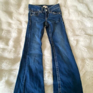 Lågmidjade jeans med slitning - jättesnygga blåa jeans från Gina Tricot ( young ) De är lågmidjade med knappfickor på baksidan, och har ett litet hål på vänstra låret!! Det är storlek 140 och säljer pga att de är försmå! 