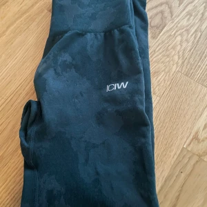 Svarta leggings från ICANIWILL - Snygga svarta leggings från ICANIWILL med diskret mönster och logga på benet. Perfekta för träning eller en avslappnad dag. De har en tight passform som ger bra stöd och komfort.
