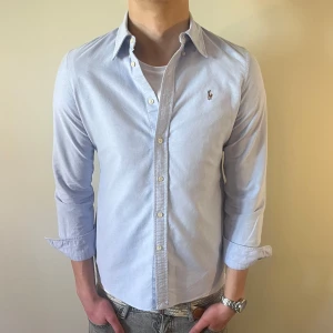 Ljusblå Ralph Lauren skjorta - Nu säljer vi ännu en fet polo skjorta som passar till alla tillställningar! Lite annorlunda formad i midjan(sista bilden)  Du ska kunna uttrycka stil utan att det kostar för mycket!🕺🍾💼🤩  Storlek👔: M Nypris💰:  ca 1499 kr
