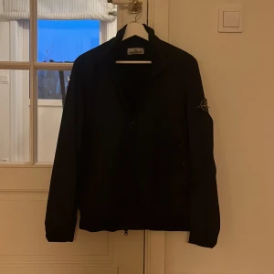 Mörkblå jacka från Stone Island - Säljer en stilren mörkblå jacka från Stone Island. Den är ganska tunn och fungerar perfekt vid kalla sommardagar, klassiskt vårväder samt mer blötare höst. Den är i storlek S och passar nog den i ungefär 170-175 cm snåret, annars kan den nog bli lite kort. Jackan i sig har nästan inga indirekta skador och köptes i Amsterdam. På en seriös affär, ungefär som en NK fast i Amsterdam. Priset kan diskuteras vid lämpligt förslag och ändast seriösa köpare. Köptes för 400 euro på rea sommaren 2022