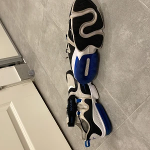 Nike Air Max sneakers i svart och blått - Snygga Nike Air Max sneakers i svart, blått och vitt. Skorna har en modern design med synlig Air Max-dämpning och snörning. Perfekta för en sportig look.