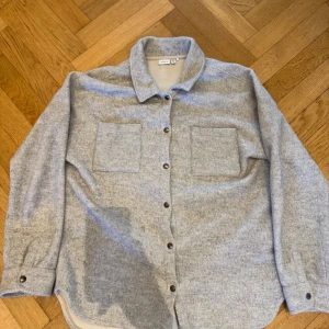 Grå overshirt  - Snygg grå overshirt med två bröstfickor och knappar framtill. Perfekt för vår och sommar. Storlek 158-164 men sitter som en xs/s. Skick 8/10 använd. Pris går att diskutera vid snabb affär💰vid funderingar eller frågor hör av dig!