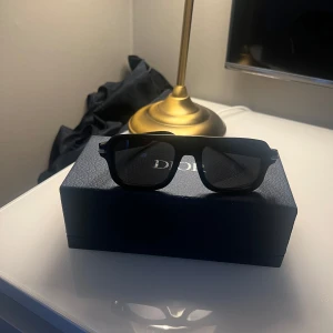 Svarta solglasögon från Dior - Snygga svarta solglasögon från Dior med en stilren design. De har en rektangulär form och är perfekta för en trendig look. Kommer med ett elegant fodral. Köpt från Nk Göteborg 
