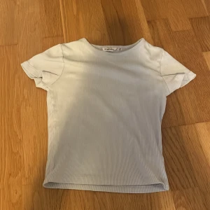 Vit ribbad topp från KappAhl - Säljer en stilren vit ribbad topp från KappAhl. Toppen har korta ärmar och en rund halsringning, perfekt för en enkel och snygg look. Passar bra till både jeans och kjol. 🌟