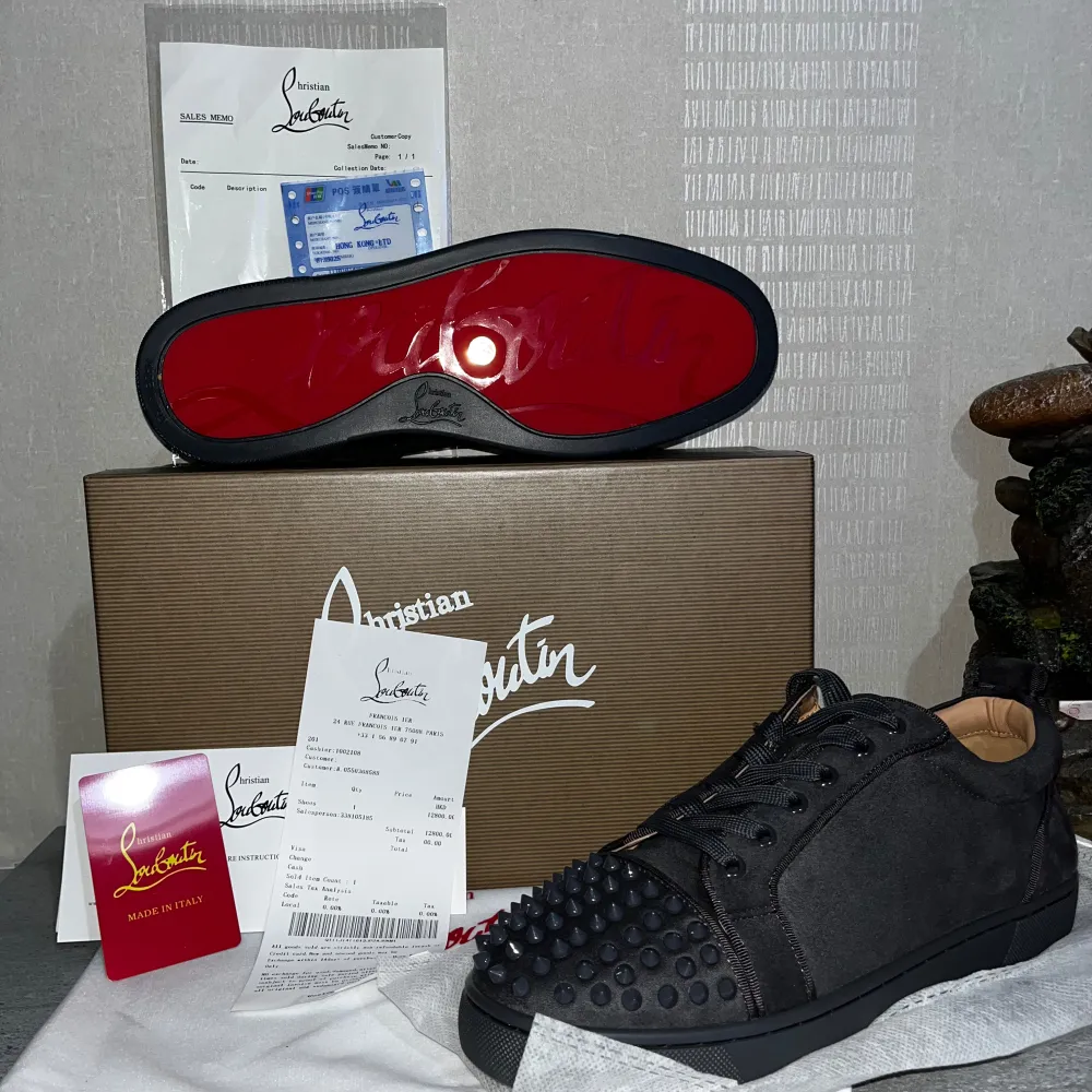 Snygga svarta sneakers från Christian Louboutin med ikoniska röda sulor. Skorna har en unik design med nitar på tån och är tillverkade i skinn. Perfekta för att ge din outfit en edgy touch.. Kengät.