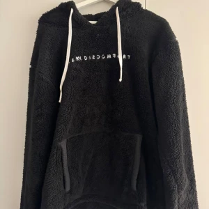 Svart fleece hoodie från Seek Discomfort | KNAPPT ANVÄND - Mysig svart hoodie i fleece från Seek Discomfort med texten 'Seek Discomfort' på framsidan. Tröjan har en stor huva och en praktisk magficka. Tröjan är endast använd ett fåtal gånger.