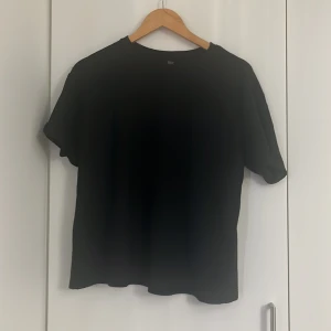 Svart ribbad t-shirt från SHEIN - En svart ribbad t-shirt från SHEIN i storlek S. T-shirten har korta ärmar och en klassisk rund halsringning. Materialet är ribbat vilket ger en snygg struktur och lite stretch. Perfekt till jeans eller kjol.