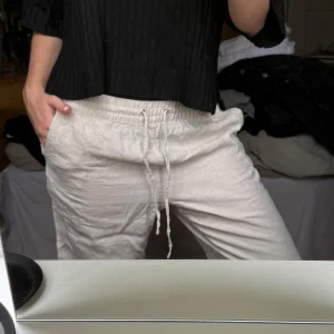 Beiga linnebyxor med dragsko - Säljer ett par beiga linnebyxor med elastisk midja och dragsko. Byxorna har en avslappnad passform och är perfekta för varmare dagar. Lätta och luftiga med klassisk look.