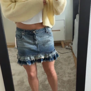 Low waist Jeanskjol med volang från Nelly - Säljer en blå jeanskjol från Nelly med volangdetalj längst ner. Kjolen har klassisk femficksdesign, knapp och dragkedja framtill samt råa kanter vid volangen. Perfekt för dig som gillar denim med en twist. Kjolen har en låg midja och är aldrig använd (lappen är kvar) 💓 
