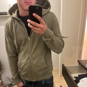 Olivgrön hoodie med dragkedja från Colorful Standard - Säljer en olivgrön hoodie från Colorful Standard i storlek S. Säljer på grund av att den inte kommer till användning.