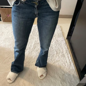 Lågmidjade bootcut jeans - Snygga blå jeans från Lee med klassisk bootcut-passform. Jeansen har låg midja och femficksdesign med Lee-logga på bakfickan, de är sydda vid bakfickan. Perfekta till vardags för en avslappnad men stilren look.