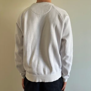 Vit sweatshirt från Race Marine - Vit sweatshirt från Race Marine med svart tryck framtill. Tröjan har rund halsringning och långa ärmar. Perfekt för en avslappnad stil och enkel att matcha med andra plagg. Skriv kring mer information😀