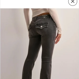 Grå bootcut jeans från True Religion - Intressekoll på ett par grå jeans från True Religion med bootcut-passform. Jeansen har klassiska fickor med lock och knapp bak samt låg midja jag säljer för att får tyvärr inte användning för dem längre. De är som nya inga tecken på användning🥰🥰