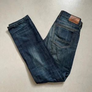 Mörkblå jeans från River Island - Säljer ett par mörkblå jeans från River Island med  raka ben. Jeansen passar dig som gillar en tidlös och enkel stil. Stl 28/34