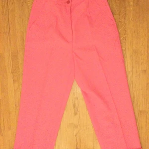 Rosa 3/4 byxor Stl: 36 - Byxa med knapp och dragkedja i gylf 100% polyester Beninnerlängd: 62 cm Midja: 68 cm 2 sidfickor fram. Oanvända!  Katter finns i hemmet 